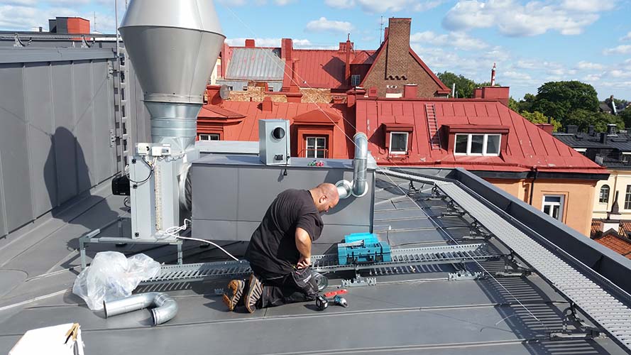 En man arbetar med ventilation på ett tak